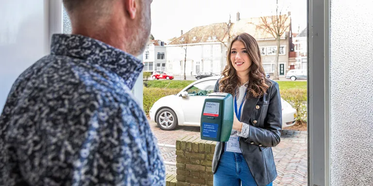 vrouw met collectebus aan de deur