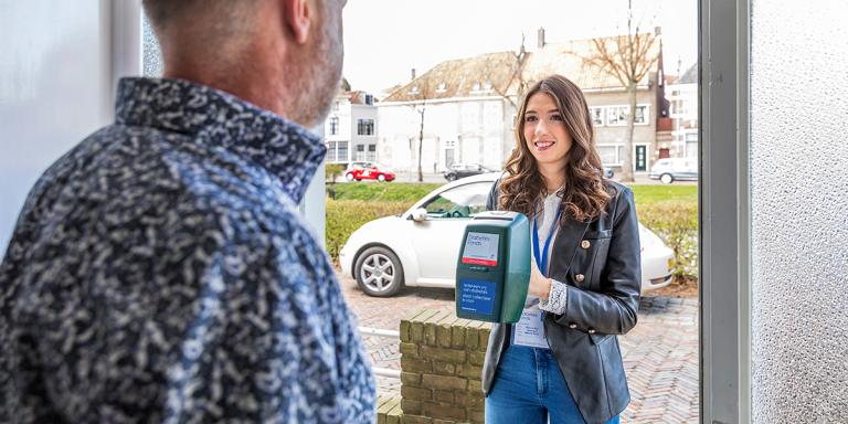 vrouw met collectebus aan de deur