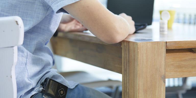 Man met insulinepomp, achter laptop