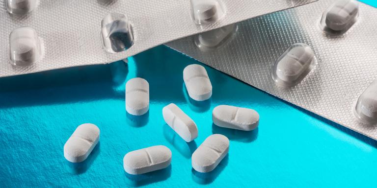witte pillen uit strip op blauwe achtergrond