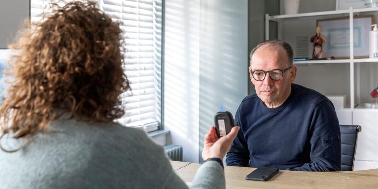 Man bij dokter die uitslag bloedtest toont
