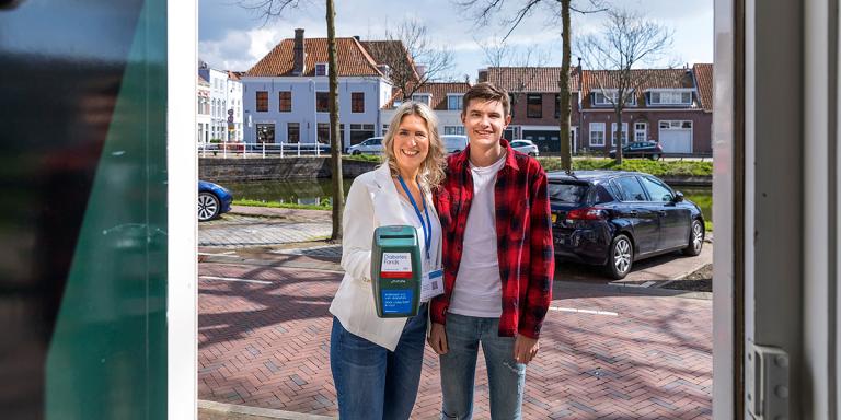 vrouw en zoon met collectebus aan een open voordeur