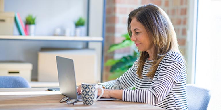 Vrouw aan tafel achter laptop