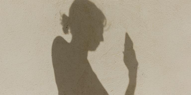 schaduw op strand van vrouw die naar mobiel kijkt