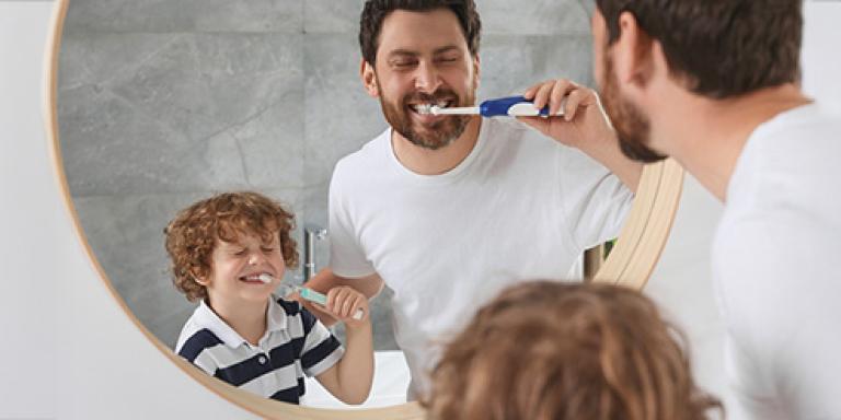 Vader en zoon poetsen tanden voor de spiegel