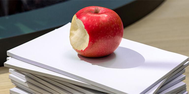 appel met een hap eruit op een stapel papier