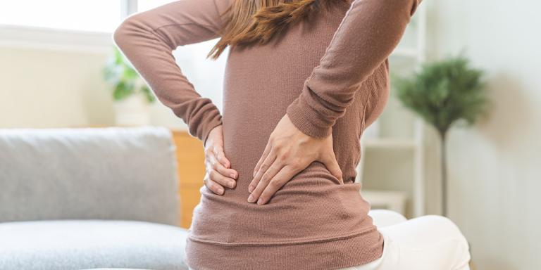 Vrouw wrijft over haar rug ter hoogte van de nieren