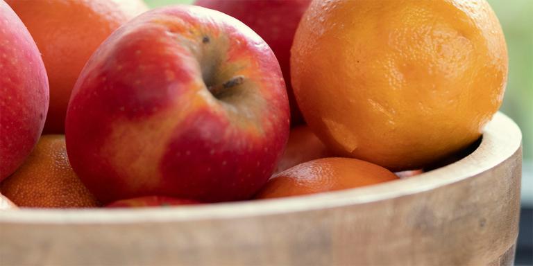 Appels en sinaasappel in een houten schaal