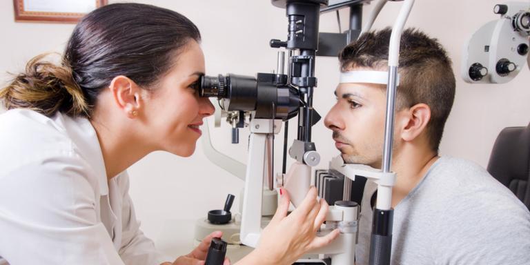 Optometrist bekijkt ogen van man
