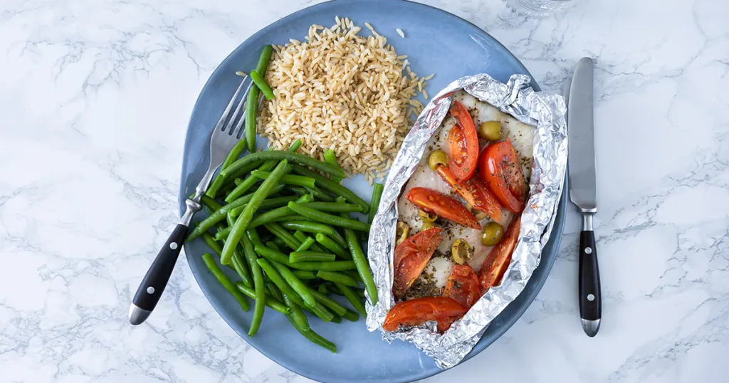 Een vispakketje met tomaten en olijven,  sperziebonen en zilvervliesrijst