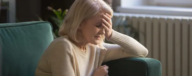 Vrouw op groene bank met hoofdpijn