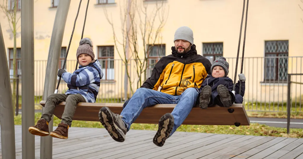 Man en kinderen op een grote schommel