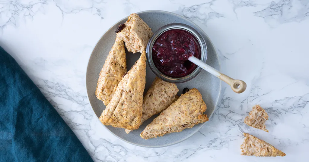 Volkoren scones op een bord met een bakje jam zonder toegevoegde suikers ernaast