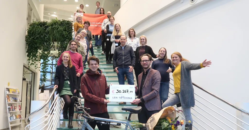 Lennart biedt cheque aan omringt door medewerkers van het Diabetes Fonds