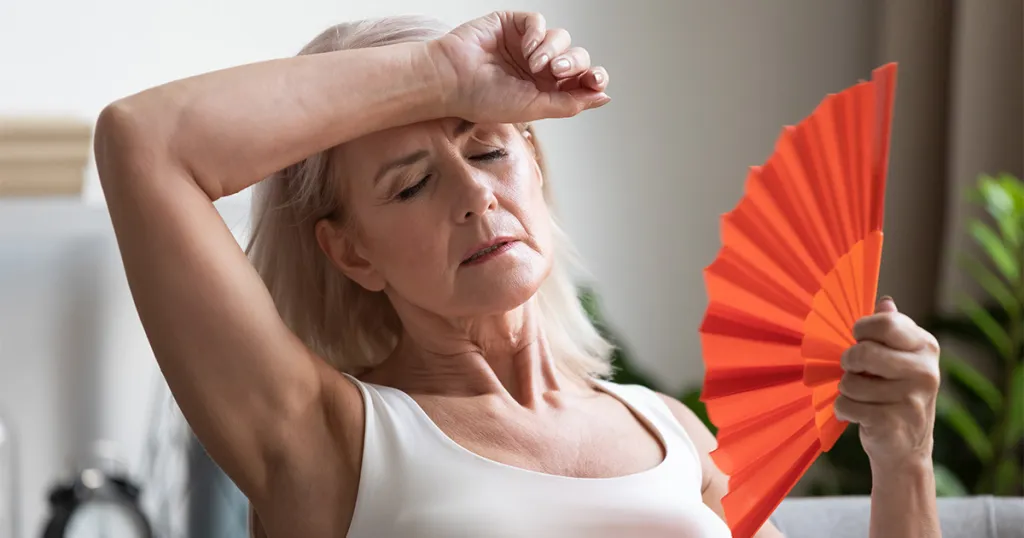 Vrouw in de overgang met waaier tegen opvlieger