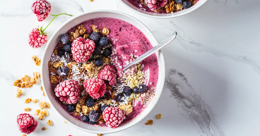 Foto vegetarisch ontbijt van smoothiebowl met frambozen, bosbessen en kokos