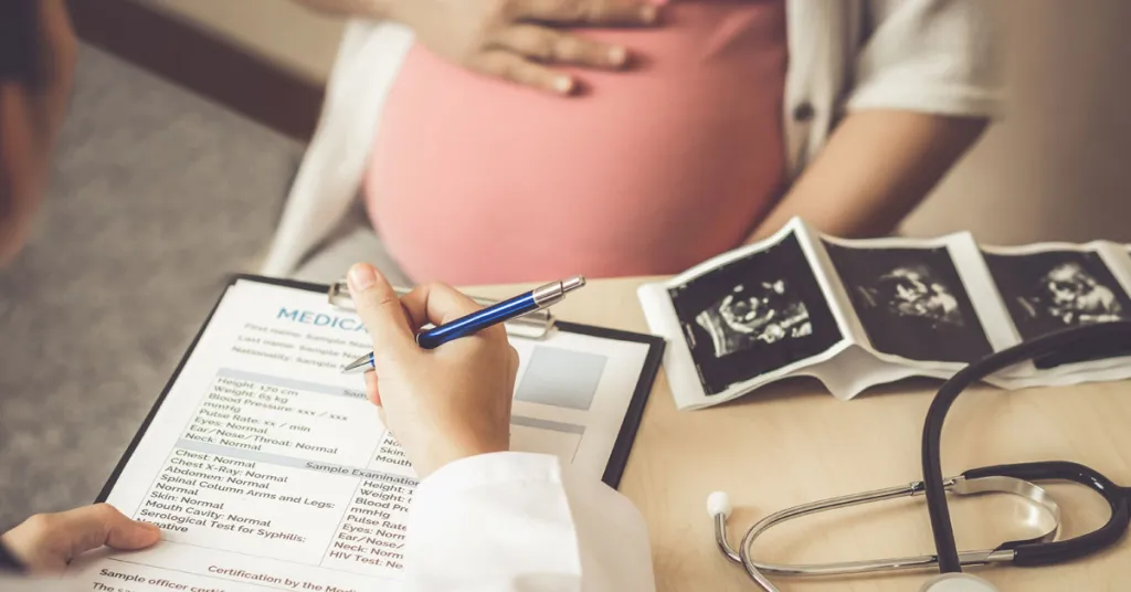 Foto Zwangere vrouw bij dokter met vragenlijst en echo op bureau