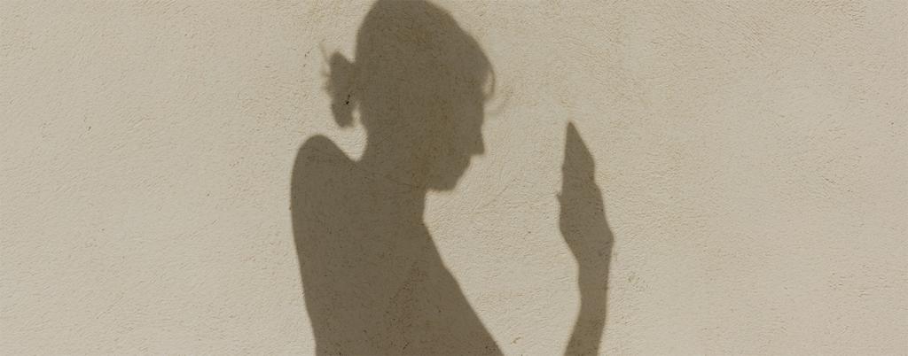 schaduw op strand van vrouw die naar mobiel kijkt