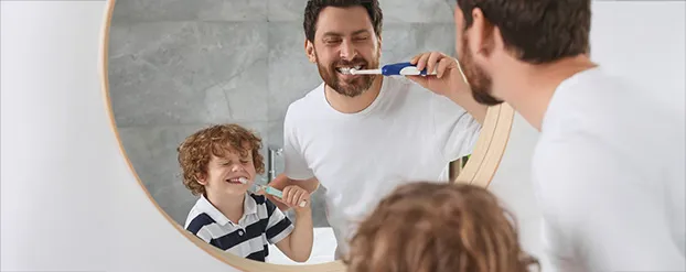 Vader en zoon poetsen tanden voor de spiegel