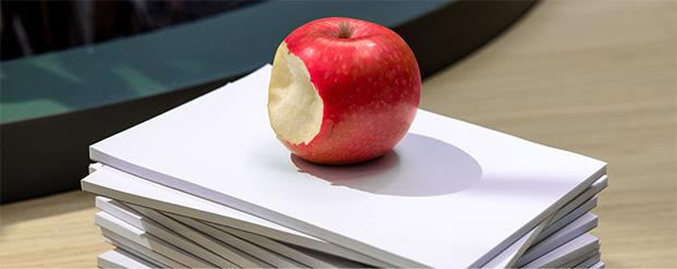 appel met een hap eruit op een stapel papier