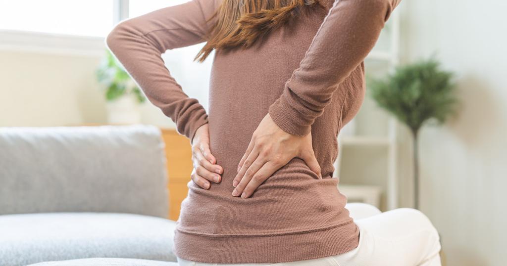 Vrouw wrijft over haar rug ter hoogte van de nieren