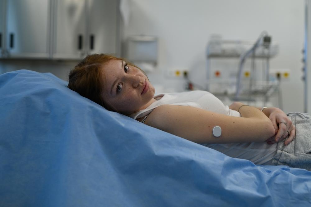 Vrouw met glucosesensor ligt op ziekenhuisbed