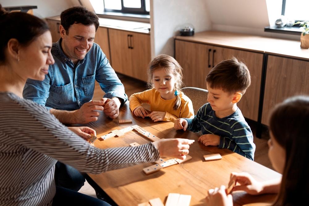 Gezin met drie kinderen doet een spelletje aan tafel