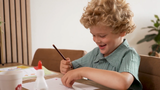 Lucas met diabetes type 1 zit vrolijk aan tafel te tekenen
