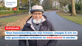 Achiekoela aan het wandelen, op de achtergrond een weg met bomen
